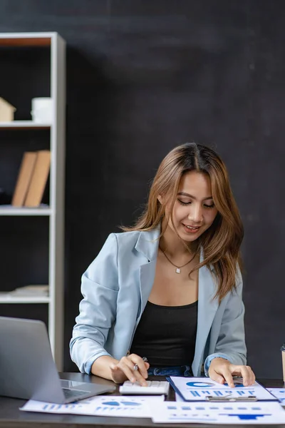 Business woman using calculator for math finance on wooden table and business background, tax, accounting, statistics and analytical research concepts in office.