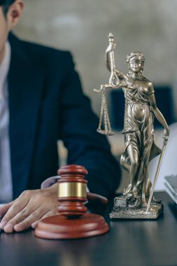 Sözleşme belgeleri ve altın tanrıça terazileri üzerinde çalışan bir avukat. Masasında çekiçle tavsiye, adalet ve hukuk müşaviri imajı sunan bir avukat..