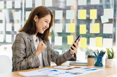 Asyalı kadınlar ofiste mali muhasebe işleri için akıllı telefonlar ve dizüstü bilgisayarlar kullanıyorlar..