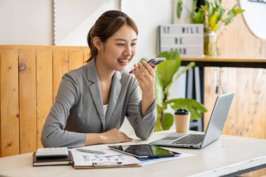 Asyalı kadınlar ofiste mali muhasebe işleri için akıllı telefonlar ve dizüstü bilgisayarlar kullanıyorlar..