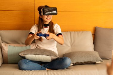 Asyalı kadın 3 boyutlu VR gözlük takıyor. Gülümsüyor ve evinde eğleniyor. Sanal konseptler ve oyun metaverleri.