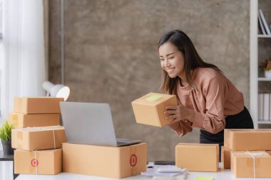 Çevrimiçi KOBİ iş ve dağıtım konsepti, gülümseyen kız, güzel sahibi, Asyalı serbest çalışan, online alışveriş KOBİ işi evdeki masada paket kutularıyla dizüstü bilgisayarda çalışıyor..