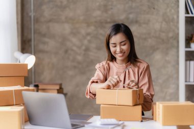 Çevrimiçi KOBİ iş ve dağıtım konsepti, gülümseyen kız, güzel sahibi, Asyalı serbest çalışan, online alışveriş KOBİ işi evdeki masada paket kutularıyla dizüstü bilgisayarda çalışıyor..