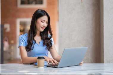 Güzel Asyalı kadın bir kafede dizüstü bilgisayarın üzerinde çalışıyor.