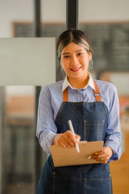 Asyalı kadınlar bir kahve dükkanında müşterileri karşılamak için bir dükkan açmak için bir tabela astılar. Küçük işletme sahibi ve işletmeciler ve kahve dükkanları yiyecek ve içecek konsepti