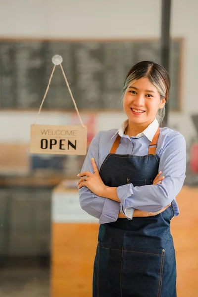 Asian women set up a sign to open a shop to welcome customers at a coffee shop. small business owner and startups and coffee shops food and drink concept