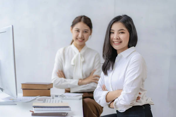 Two Asian businesswomen attending two Asian business partners discuss the financial and company planning graph during a budget meeting.