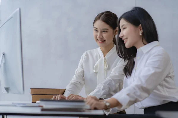 Two Asian businesswomen attending two Asian business partners discuss the financial and company planning graph during a budget meeting.