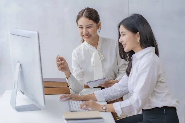 Two Asian businesswomen attending two Asian business partners discuss the financial and company planning graph during a budget meeting.