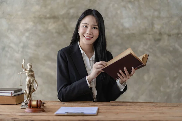 Young Asian lawyer working in office with laptop concept of justice and law. lawyer workAbout the contract documents of brass scales on a wooden table Legal services, advice, justice
