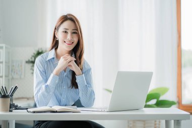 Asyalı iş kadını evdeki müşterilerle internet üzerinden iletişim kuruyor. ev konseptinden çevrimiçi çalışma