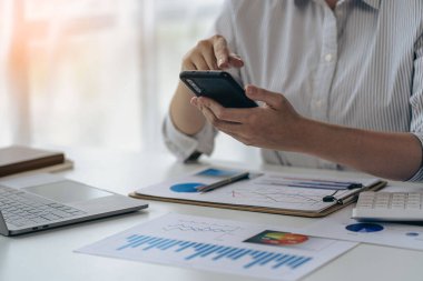 İş yerinde akıllı telefonları tutan iş adamları ve kadınlar. Proje istatistikleri. Mali veri satışı tablosu masada. yakın çekim görünümü