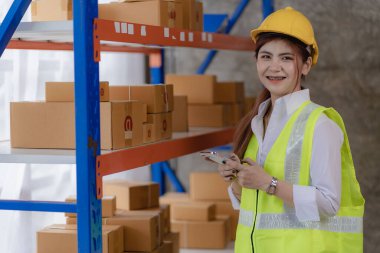 Asyalı kadın çevrimiçi satıcılar müşterilere göndermeden önce stok ve stokları kontrol ederler. Bir ecommerce işletmesi sahibi bir depoda çalışıyor..