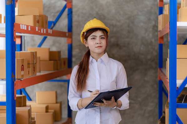 Азиатка проверяет посылку с полки маленького склада. Интернет-магазин логистических услуг для доставки товаров. Проверьте штрих-код перед отправкой.