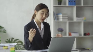 Asyalı kadın muhasebeci dizüstü bilgisayar ve akıllı telefon ile finansal grafik analizi üzerinde çalışıyor..