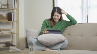 Sosyal medya, online ve Asyalı kadınlar evdeki kanepede dizüstü bilgisayar oynuyorlar İnternet üzerinden alışveriş yapan kızlar