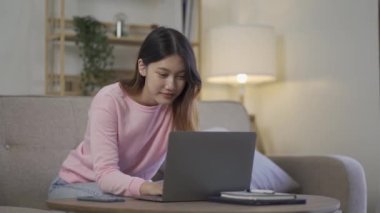 Sosyal medya, online ve Asyalı kadınlar evdeki kanepede dizüstü bilgisayar oynuyorlar İnternet üzerinden alışveriş yapan kızlar