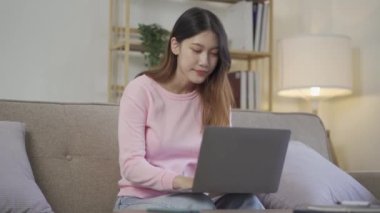 Sosyal medya, online ve Asyalı kadınlar evdeki kanepede dizüstü bilgisayar oynuyorlar İnternet üzerinden alışveriş yapan kızlar