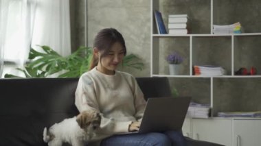 Sosyal medya, online ve Asyalı kadınlar evdeki kanepede dizüstü bilgisayar oynuyorlar İnternet üzerinden alışveriş yapan kızlar