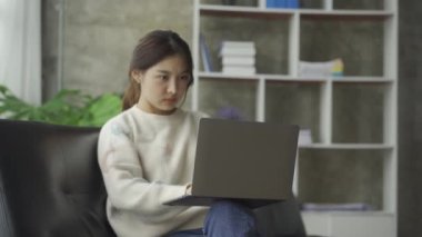 Sosyal medya, online ve Asyalı kadınlar evdeki kanepede dizüstü bilgisayar oynuyorlar İnternet üzerinden alışveriş yapan kızlar