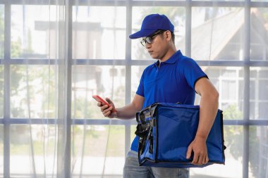 Teslimatçı mavi bir üniforma ve bir çanta giyiyordu. Yiyecek ya da paket teslimatı. Teslimatçı veya ekspres paket beyaz arka planda izole.