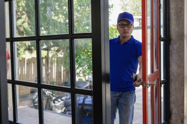 Teslimatçı mavi bir üniforma ve bir çanta giyiyordu. Yiyecek ya da paket teslimatı. Teslimatçı veya ekspres paket beyaz arka planda izole.