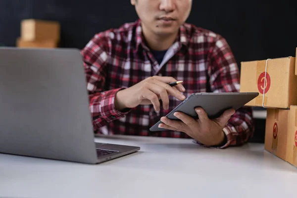 Young Asian men start selling online with boxes and laptops for taking orders and shipping parcel boxes, SME business idea.