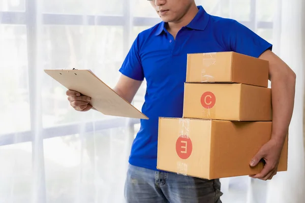 Picture of happy young man in blue hat and blue t-shirt standing with yellow boxes isolated on white background, delivery concept.