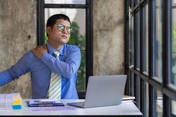 Health and Medicine Concept Office Syndrome Asian businessman working on a laptop computer has a problem with shoulder pain. Feeling pain after sitting at your desk for a long time