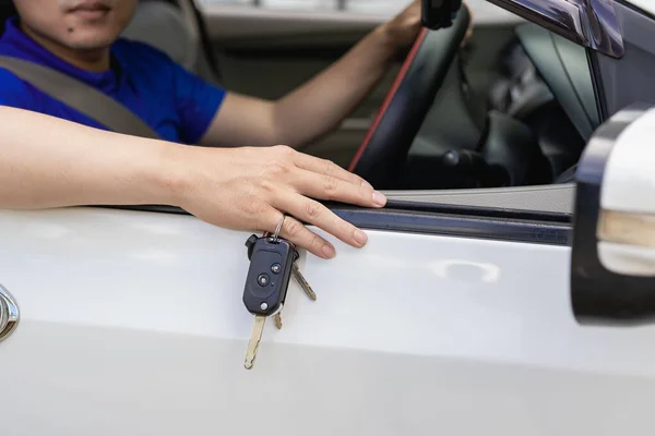 A handsome young man in a blue t-shirt in a hat holding his new car keys and smiling. Asian man with car keys in hand . The idea of having a new car.