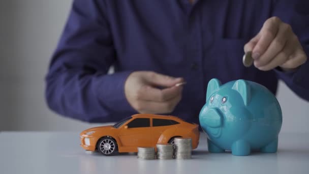 一个年轻人把一枚硬币放在储蓄罐里 准备买一辆未来的汽车 4K节约想法 — 图库视频影像