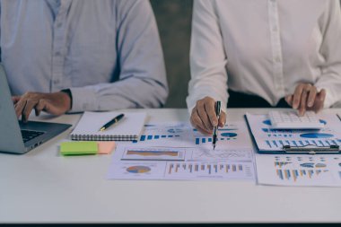 Ofiste finansal analiz ve pazarlama stratejileri üzerinde çalışan bir iş adamı ekibi. Masada dizüstü bilgisayar finans grafik belgesi ile takım çalışması