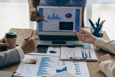 Ofiste finansal analiz ve pazarlama stratejileri üzerinde çalışan bir iş adamı ekibi. Masada dizüstü bilgisayar finans grafik belgesi ile takım çalışması