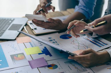 Ofiste finansal analiz ve pazarlama stratejileri üzerinde çalışan bir iş adamı ekibi. Masada dizüstü bilgisayar finans grafik belgesi ile takım çalışması