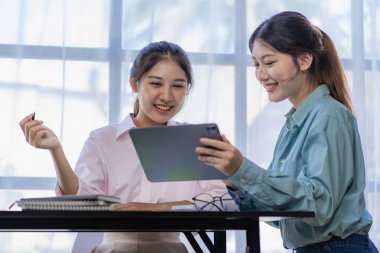 İki genç Asyalı kadın yeni bir başlangıç projesi konseptini tartışıyor. Dizüstü bilgisayarlarda finansal planlama, istatistik ve yatırım pazarının analizi