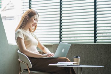 Asyalı kadınlar internetten internetten kahve almak için dizüstü bilgisayar kullanıyor. İnternette sohbet eden ve bilgisayarına bakan bir kız.