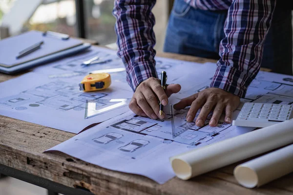 A close-up view of engineers drawing plans and measurements at work. Architects design, work, draw, sketch, and model architectural construction in the home.
