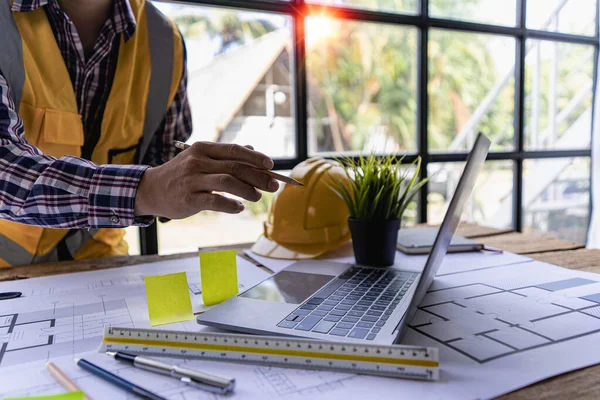 A close-up view of engineers drawing plans and measurements at work. Architects design, work, draw, sketch, and model architectural construction in the home.