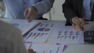 Finansal analiz ekibi genç Asyalı işadamı iş odaklı toplantılarda satış verilerini ekibe sunuyor. Yaratıcı iş ekibi ofiste birlikte oturuyor.