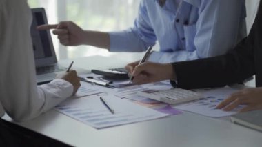 Finansal analiz ekibi genç Asyalı işadamı iş odaklı toplantılarda satış verilerini ekibe sunuyor. Yaratıcı iş ekibi ofiste birlikte oturuyor.