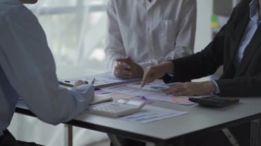 Finansal analiz ekibi genç Asyalı işadamı iş odaklı toplantılarda satış verilerini ekibe sunuyor. Yaratıcı iş ekibi ofiste birlikte oturuyor.