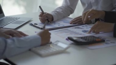 Finansal analiz ekibi genç Asyalı işadamı iş odaklı toplantılarda satış verilerini ekibe sunuyor. Yaratıcı iş ekibi ofiste birlikte oturuyor.