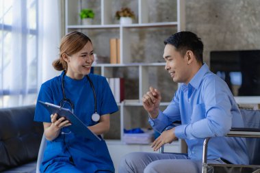 Asyalı kadın doktorlar, hastane ve klinik konseptinde danışma ve sağlık kontrolünden sonra tekerlekli sandalyedeki erkek hastaları teşvik eder ve desteklerler.