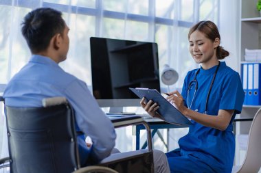 Asyalı kadın doktorlar, hastane ve klinik konseptinde danışma ve sağlık kontrolünden sonra tekerlekli sandalyedeki erkek hastaları teşvik eder ve desteklerler.