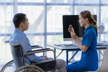 Asyalı kadın doktorlar, hastane ve klinik konseptinde danışma ve sağlık kontrolünden sonra tekerlekli sandalyedeki erkek hastaları teşvik eder ve desteklerler.