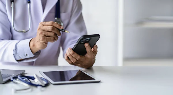 Male doctor talks to patients online via video call via webcam on computer, laptop, smartphone, tablet. Teleconference is like a teleconference.