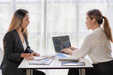 İki Asyalı iş adamı ya da muhasebeci finansal hesapları araştırıyor. İki Asyalı kadın finans danışmanı ya da analist çalışıyor. Finansal raporları birlikte tartışın.