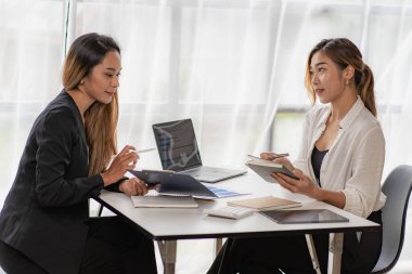 İki Asyalı iş adamı ya da muhasebeci finansal hesapları araştırıyor. İki Asyalı kadın finans danışmanı ya da analist çalışıyor. Finansal raporları birlikte tartışın.