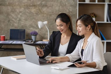 2 Asyalı kadın muhasebe kavramında dizüstü bilgisayar kullanıyor