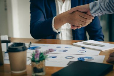 Genç işadamları ofiste el sıkışıyor ve başarılı bir takım çalışması, işbirliği ve selamlaşmayı tamamlıyorlar.